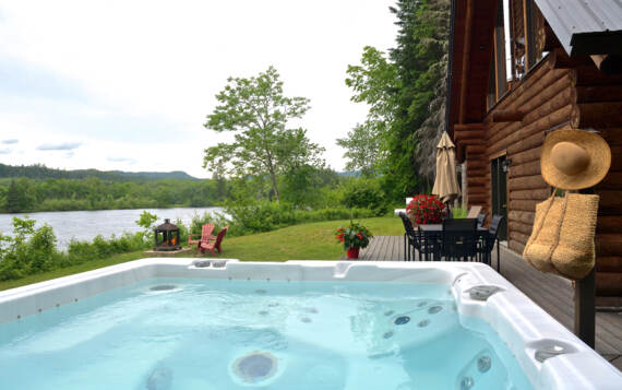 Spa privé et terrasse arrière avec ensemble patio au bord de l'eau avec vue sur rivière et montagnes Mauricie