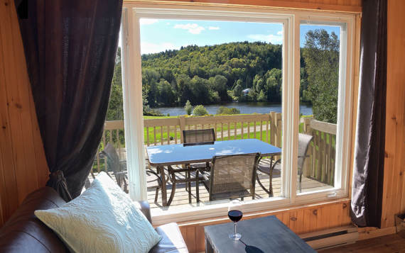 Salon avec foyer poêle à bois vitré et vue sur l'eau chalet vacances Le Vacancier pour 1 ou 2 personnes Lanaudière Chalets Booking