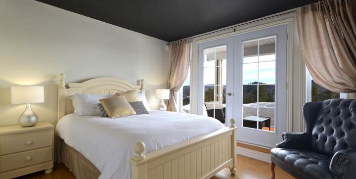 Chambre des maîtres grand lit avec portes françaises et accès terrasse couverte avec vue sur les montagnes chalet de la Montagne