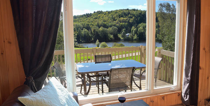 Salon avec foyer poêle à bois vitré et vue sur l'eau chalet vacances Le Vacancier pour 1 ou 2 personnes Lanaudière Chalets Booking